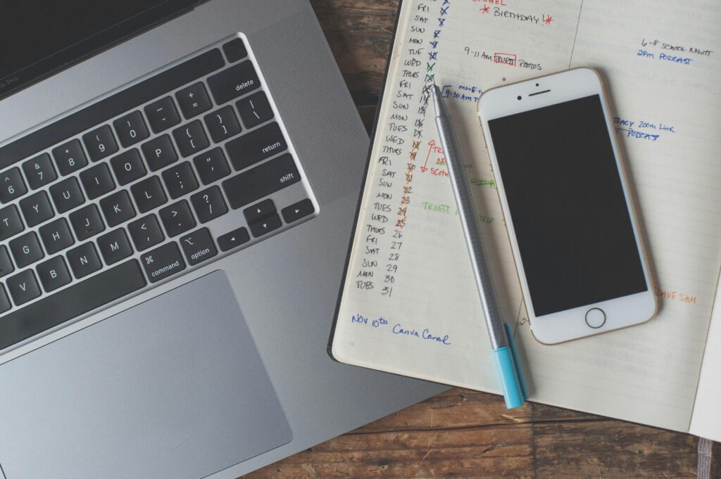 A workspace featuring a laptop, smartphone, and planner on a wooden desk, ideal for remote work.